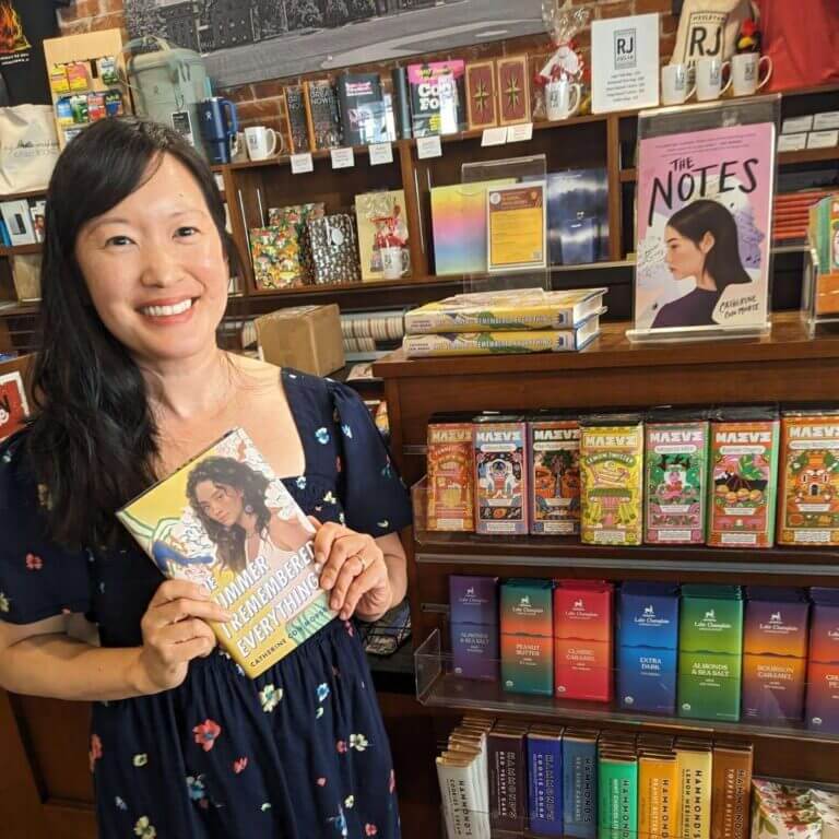 Author Catherine Con Morse poses in a bookstore with her books The Summer I Remembered Everything and The Notes.