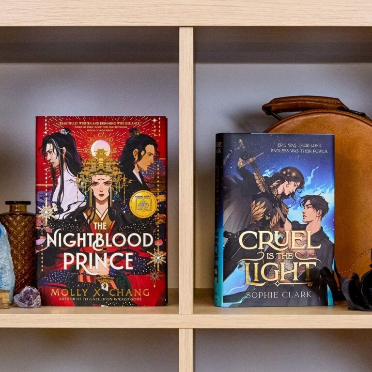 Two YA romantasy books sit beside each other on a bookshelf: The Nightblood Prince and Cruel Is the Light.